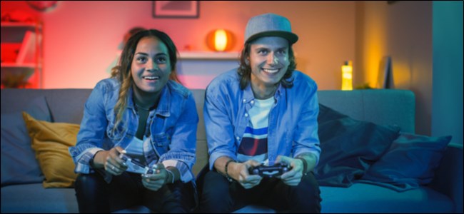 A man and woman sitting on a couch playing a video game.