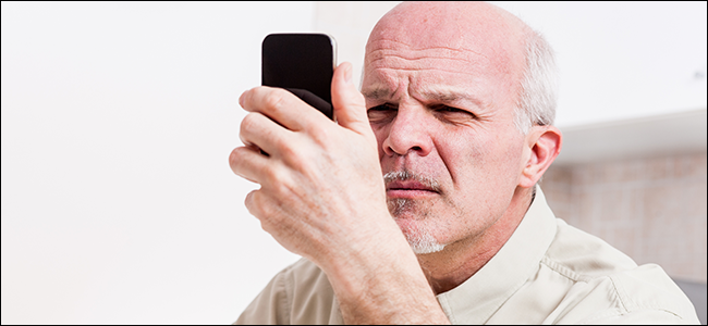 A man stares at his phone, clearly enduring some serious eyestrain.