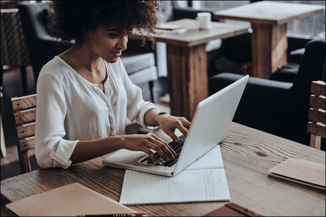 A smiling woman typing on a laptop computer.