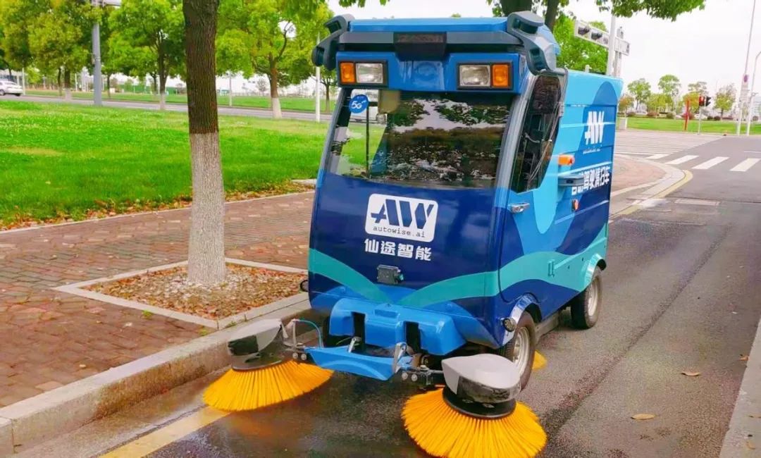 一辆蓝色小车在非机动车道上缓缓开动,车前两个巨大的黄色地刷匀速