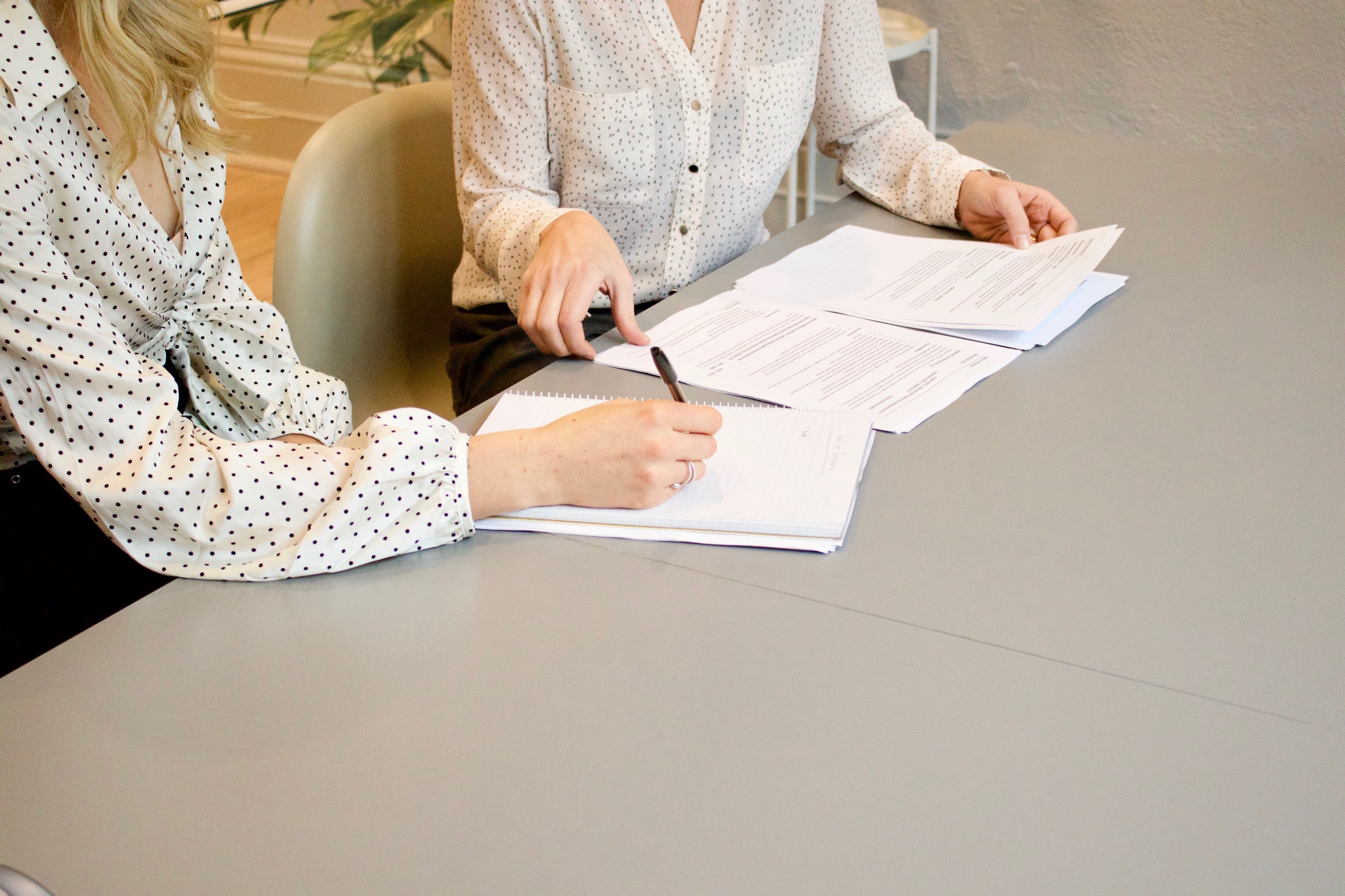 Two people reviewing papers together and taking notes.