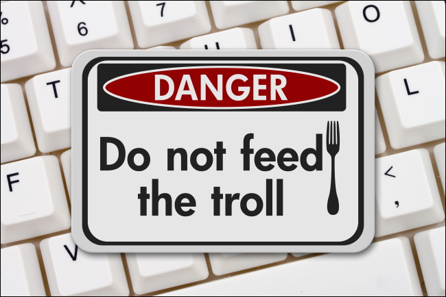 A "Danger: Do not feed the troll" sign on a computer keyboard.