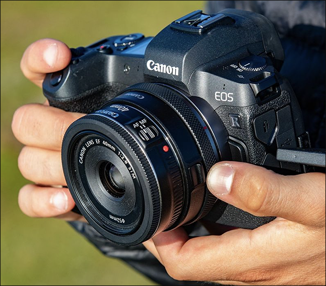 Someone holding a Canon EOS camera with a mirrorless adapter mounted on it.